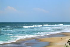 an ocean view with waves crashing on the beach