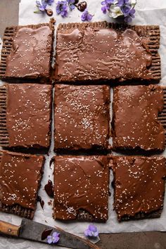 chocolate brownies cut into squares on top of parchment paper with flowers in the background