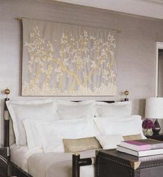 a bed with white sheets and pillows in a bedroom next to a painting on the wall