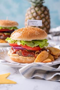 two hamburgers with lettuce, tomato and cheese on them next to chips