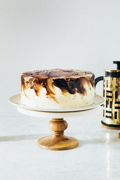 a cake sitting on top of a white plate next to a coffee pot and cup