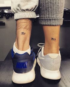 two people with matching tattoos on their feet standing next to each other, both wearing sneakers