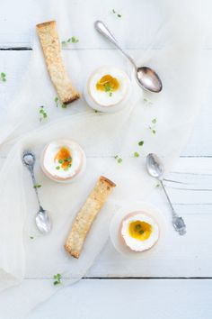 an image of eggs and crackers on a white table with spoons in the foreground