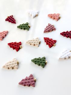 several different colored bows are arranged on a white surface with gold pins in the shape of christmas trees