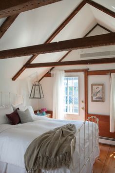 a white bed sitting in a bedroom next to a window