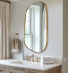 a bathroom sink with a large mirror above it and towels on the counter next to it