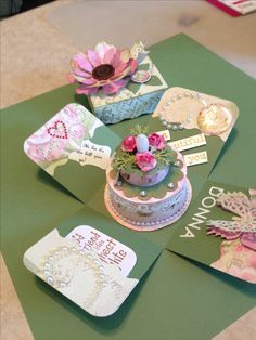 a table topped with lots of different types of cards and cakes on top of green envelopes