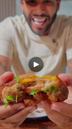 a man holding up a sandwich with lettuce and tomato on it in front of him