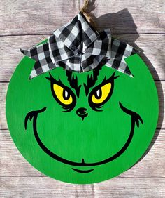 the grin face is painted on a green wooden plaque with a black and white checkered bow