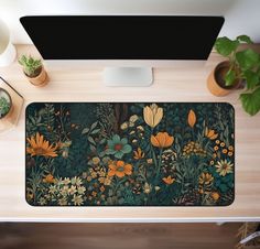 a desk with a computer monitor, keyboard and flowers on the mouse pad next to potted plants