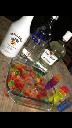 there are many gummy bears in the glass dish on the table next to bottles