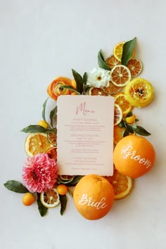 an orange wedding menu surrounded by citrus slices and flowers on a white background with the bride's name