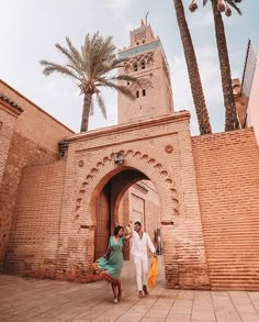 two people are walking in front of an archway