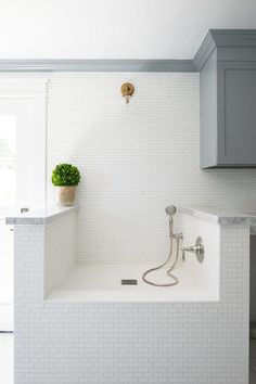 a white tiled bathroom with a shower head and faucet in the bathtub