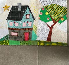 a close up of a patchwork quilt with houses and trees on the front side