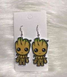 pair of earrings featuring baby groote from the avengers movie, on white background