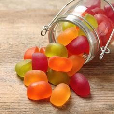 a jar filled with gummy bears sitting on top of a wooden table