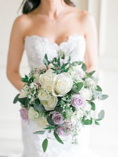 a bride holding a bouquet of white and purple flowers