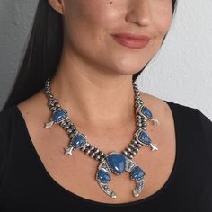 Beautiful Western Jewelry - Naturally colorful Southwestern sterling silver denim Lapis squash blossom necklace features a double strand of 8mm oxidized polished beads with seven Denim Lapis gemstones in total. There are four silver squash blossom stations with 17x13mm arrowhead-shaped denim Lapis gemstones. The large center Naja holds three soft arrowhead-shaped stones, two 15x20mm and one 26x28mm. All stones are set on scalloped bezel mountings on a floral and beaded design motif silver decora Western Blue Concho Necklace, Blue Oxidized Finish Jewelry, Blue Western Style Concho Necklace, Blue Bohemian Concho Necklace, Bohemian Blue Concho Necklace, Blue Sterling Silver Western Jewelry, Western Silver Gemstone Jewelry, Western Style Silver Gemstone Jewelry, Blue Western Sterling Silver Jewelry