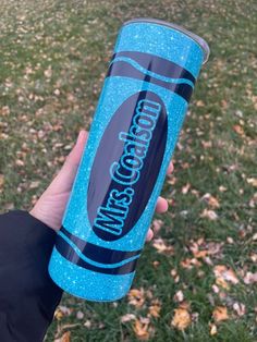 someone is holding up a blue cup with the words wisconsin on it in front of some leaves