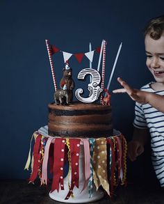 a young child pointing at a birthday cake