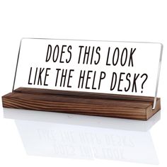 a desk sign that says does this look like the help desk? on top of a wooden block