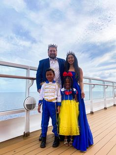 a man and two women standing next to a little boy on a deck with the ocean in the background