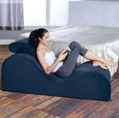 a woman sitting on a bean bag chair reading a book