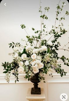 a vase filled with white flowers and greenery