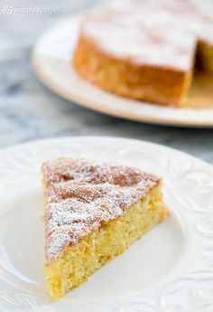 a slice of cake on a plate with powdered sugar over the top and another one in the background