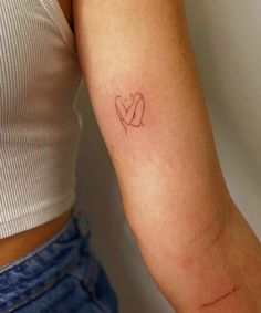 a woman's arm with a small heart tattoo on the left side of her arm