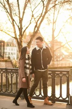 a man and woman standing next to each other on a bridge