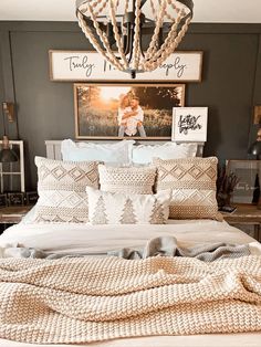 a bed with pillows and blankets on top of it next to a chandelier