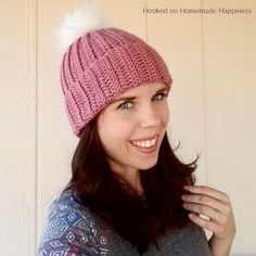 a woman wearing a pink knitted hat with white pom - pom