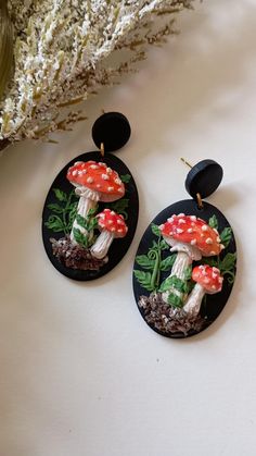 the earrings are decorated with mushrooms and plants