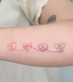 a woman's arm with three hearts on it and the word love written in different colors