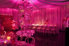 a room filled with tables and chairs covered in pink lights