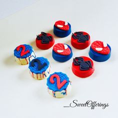 cupcakes decorated with spiderman icing and sprinkles are arranged on a white surface