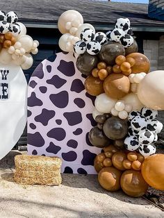 some balloons are hanging from the side of a house with cow print decorations on it