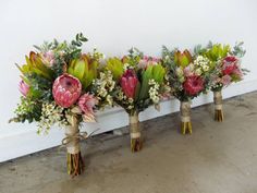 three vases filled with flowers sitting next to each other on the floor in front of a wall