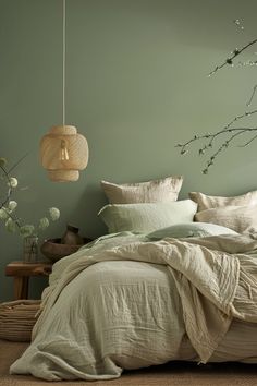 a bedroom with green walls and white linens on the bed, along with a wicker basket hanging from the ceiling