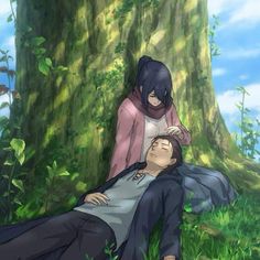 a man laying on the ground next to a woman in front of a large tree