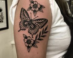 a black and white butterfly tattoo on the left upper half of the arm, with flowers around it