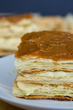 a stack of pancakes covered in peanut butter and syrup on a white plate next to another piece of cake