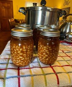 two jars filled with food sitting on top of a table next to pots and pans