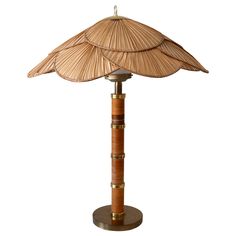 a bamboo umbrella lamp on top of a wooden stand with a white light behind it