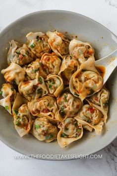 a white bowl filled with dumplings covered in sauce