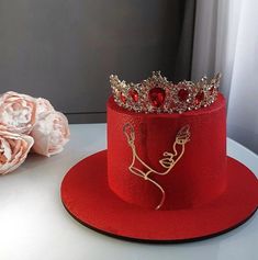 a red hat sitting on top of a white table next to flowers and a rose