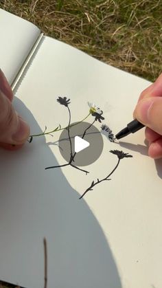 someone is drawing flowers on an open book