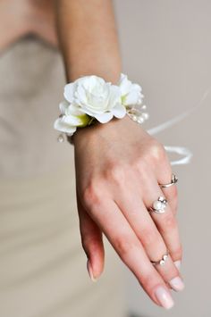 a close up of a person's hand with rings and flowers on their wrist